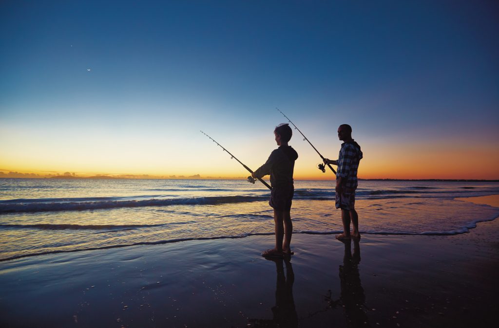 Family fishing at sunset on beach