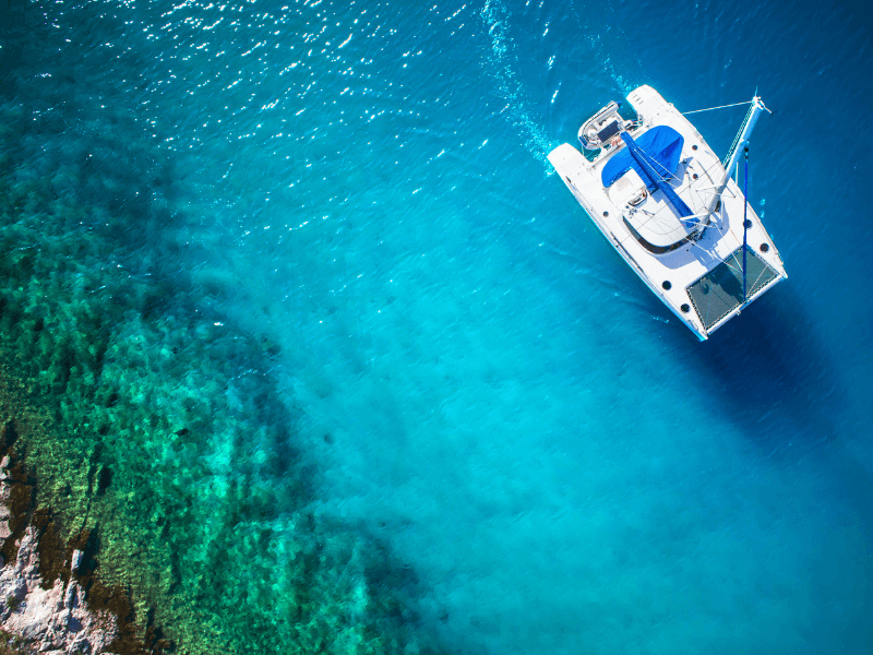 An aerial image of a catamaran over clear blue water