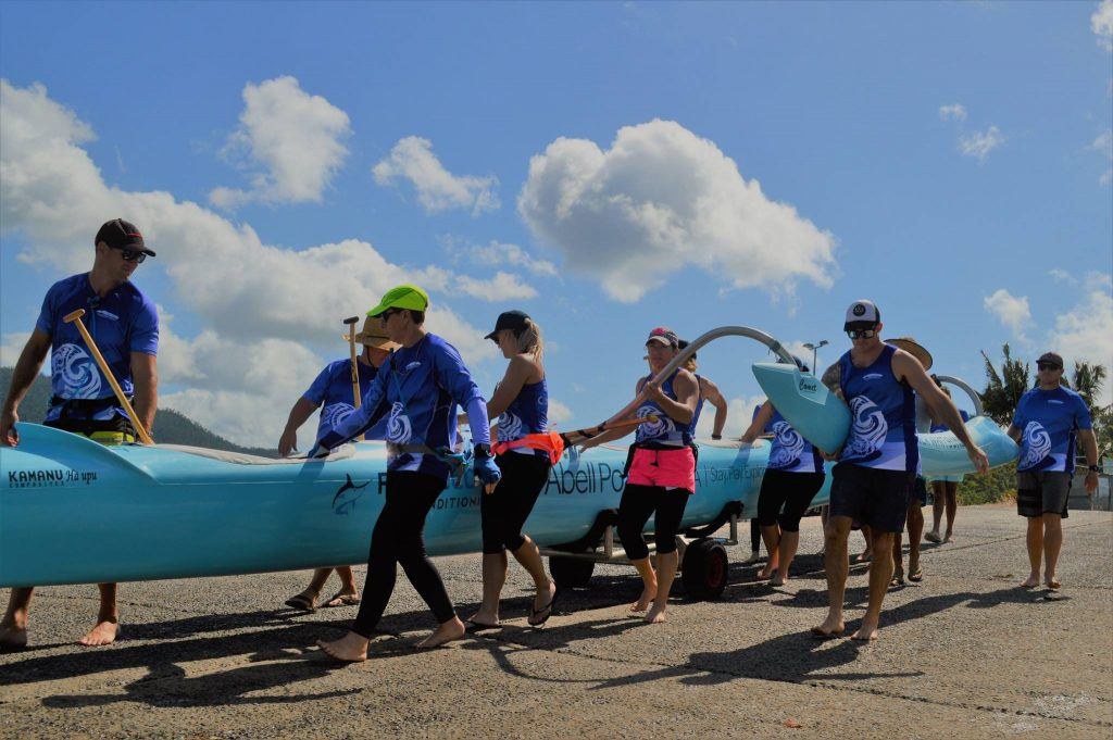 A crew of Outrigger Whitsundays carrying the outrigger vessel on the public boat ramp