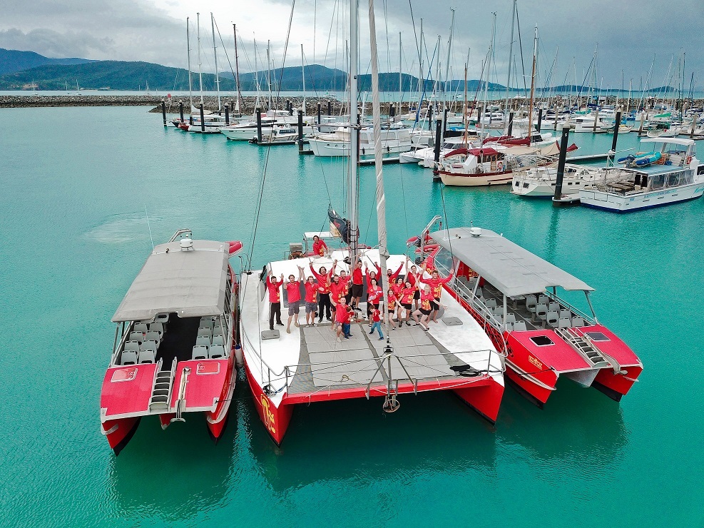 Three Red Cat Adventure vessels tied together at Coral Sea Marina with crew and staff on board