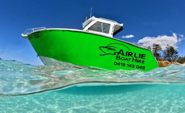 A green vessel from Airlie Boat Hire in the ocean
