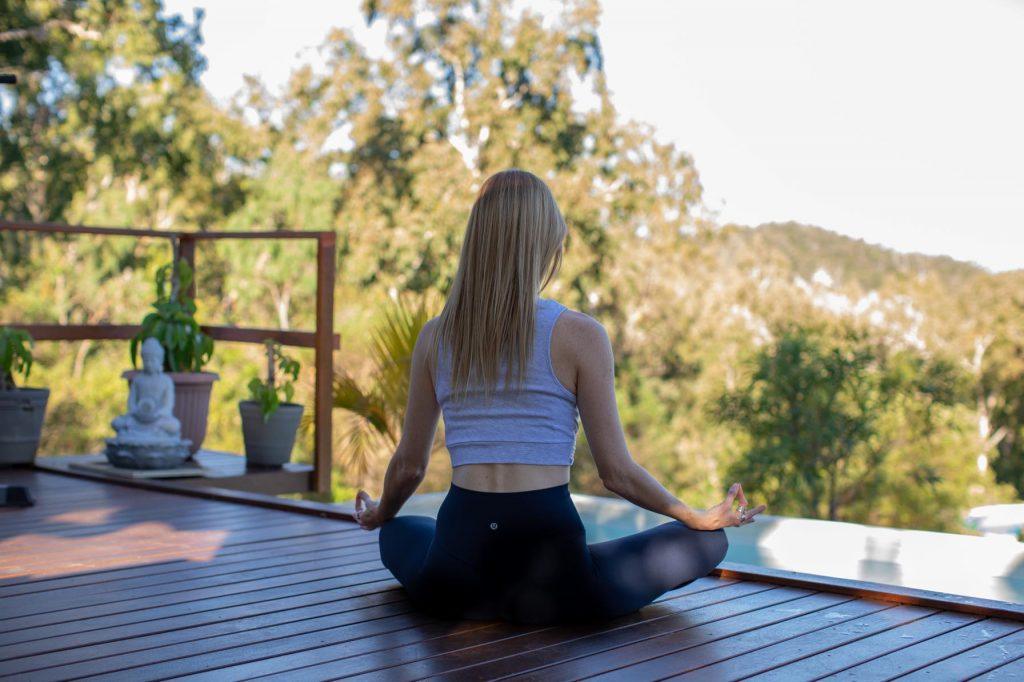 Bec Russell Yoga instructor meditating on a deck with mountain views