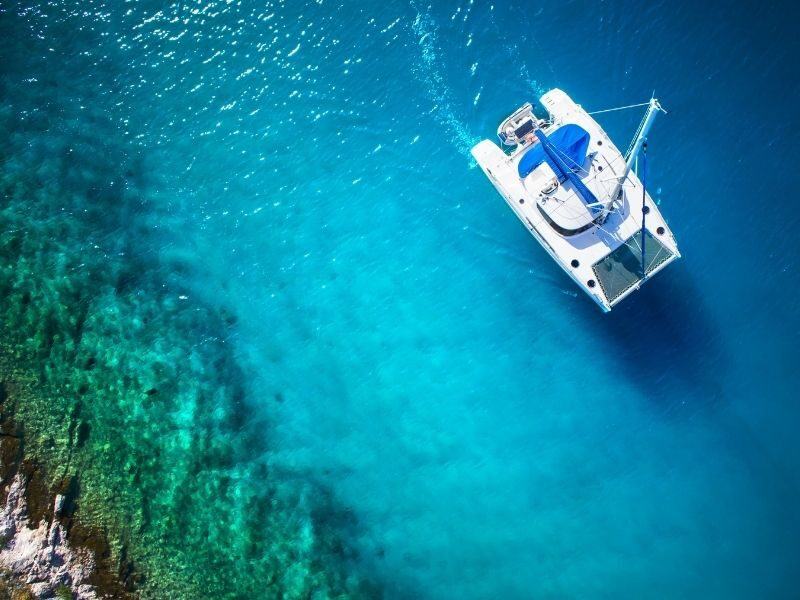Aerial image of catamaran in clear blue water near reef